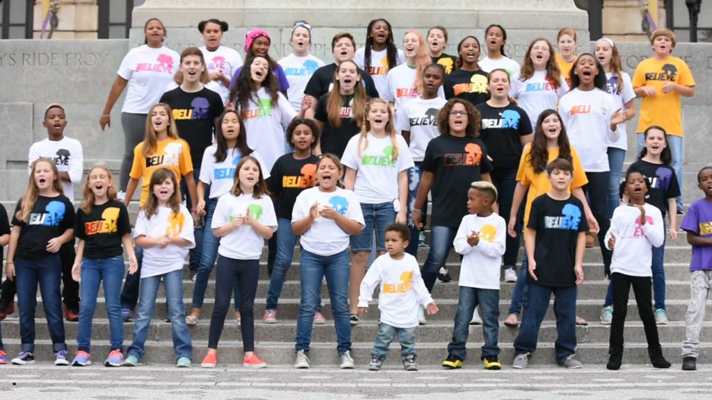 Reed’s Refuge young performers wearing Believe shirts on outdoor steps