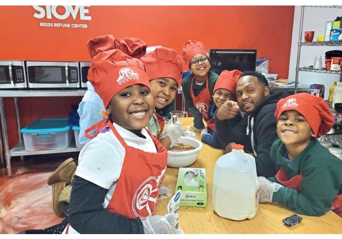Children learning culinary skills with a mentor at Reed's Refuge Center