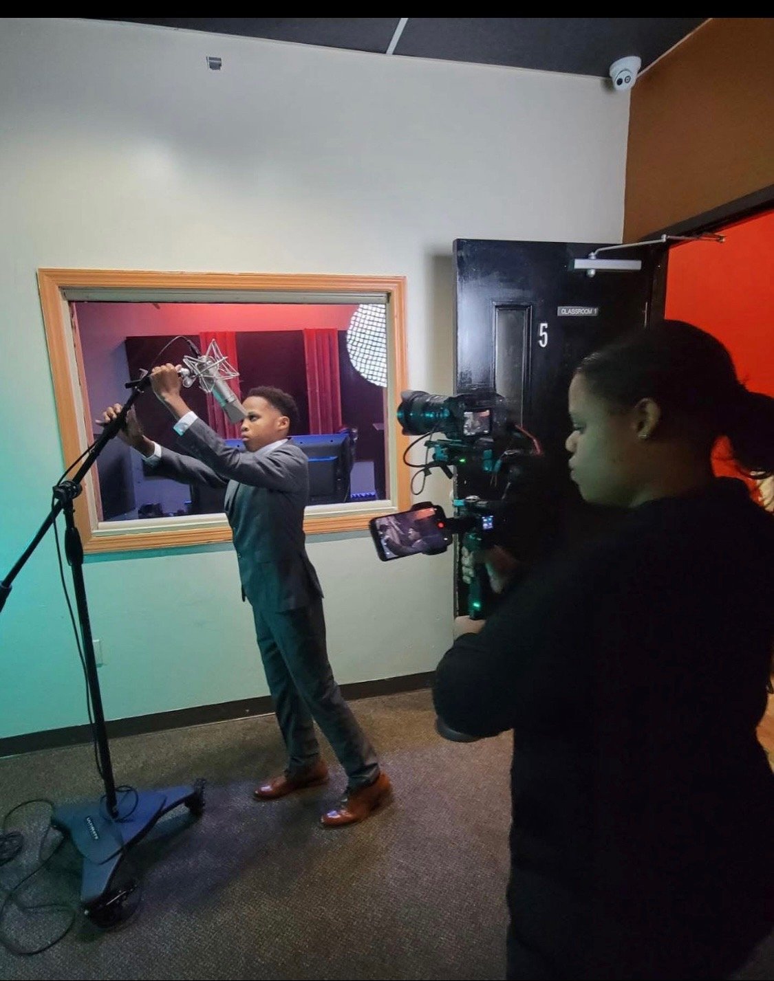 A young person preparing a microphone while a camera records at Reed’s Refuge