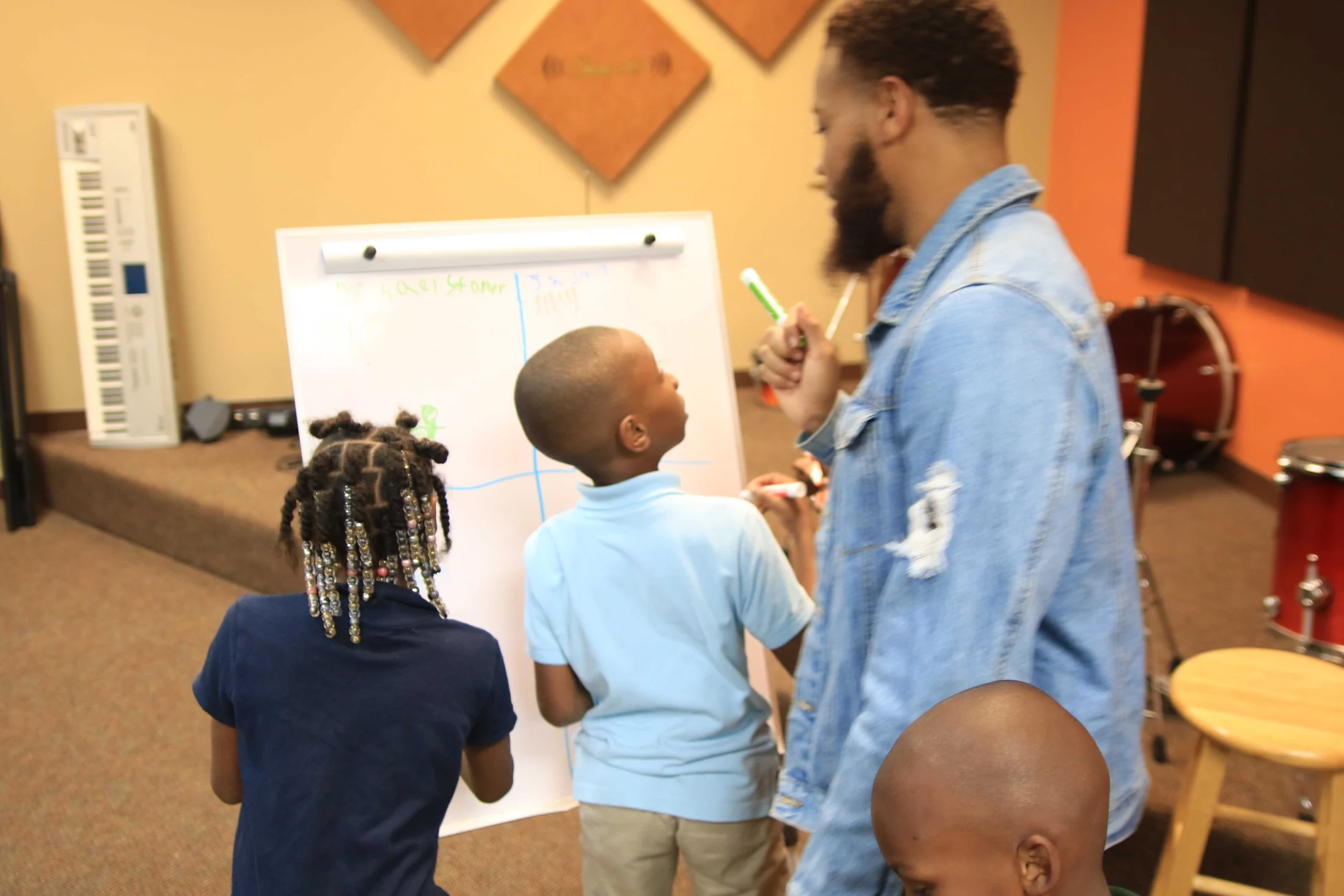 A mentor helping young people practise mathematics at a whiteboard