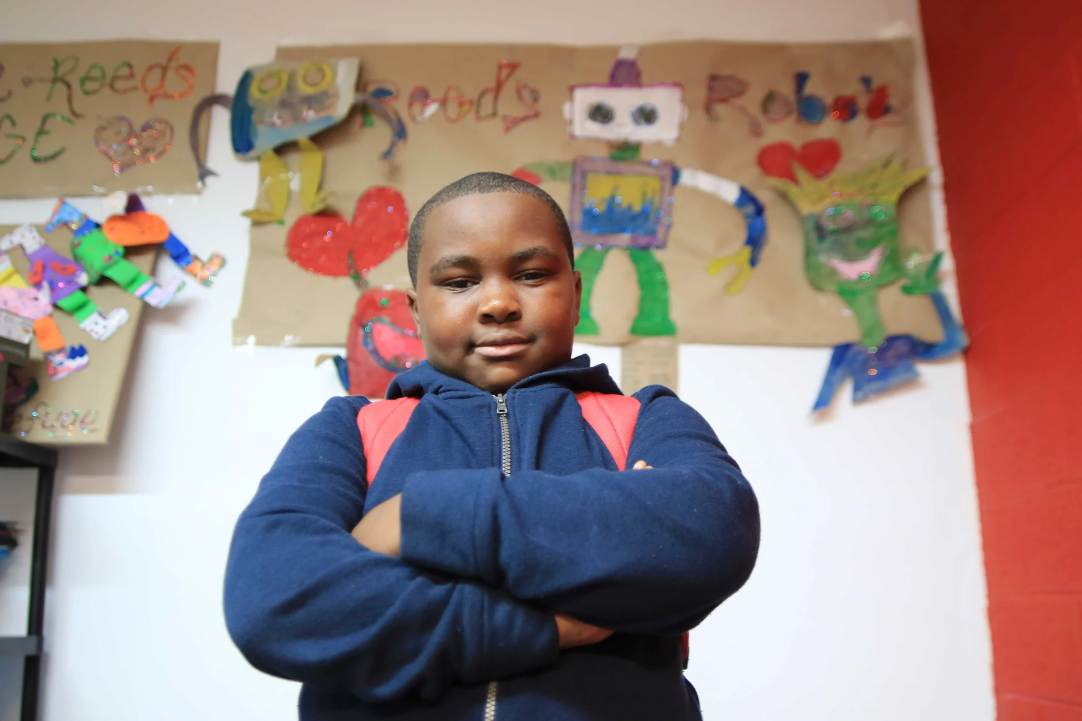 A young participant standing confidently beside creative projects at Reed’s Refuge