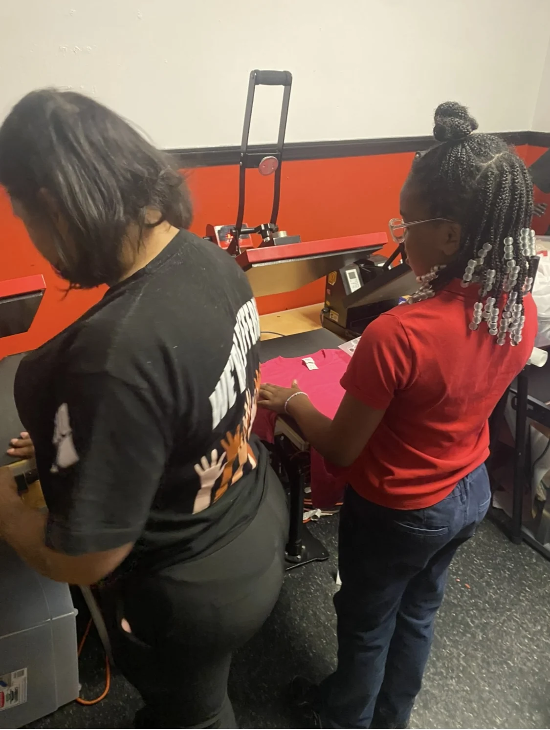 A young participant and mentor using a heat press to create a printed shirt at Reed’s Refuge