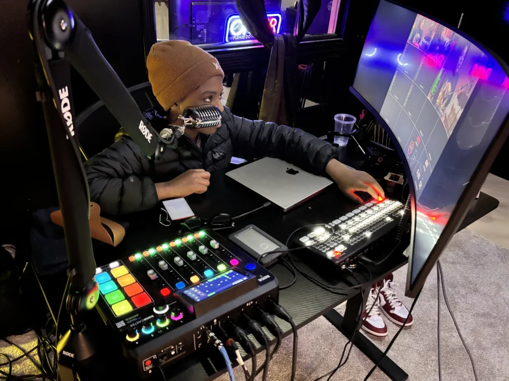 A young participant using a microphone and production console in the Reed’s Refuge media studio
