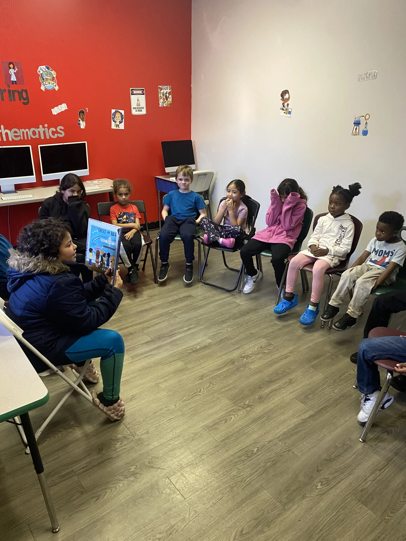 A mentor reading with children during academic enrichment at Reed’s Refuge Center