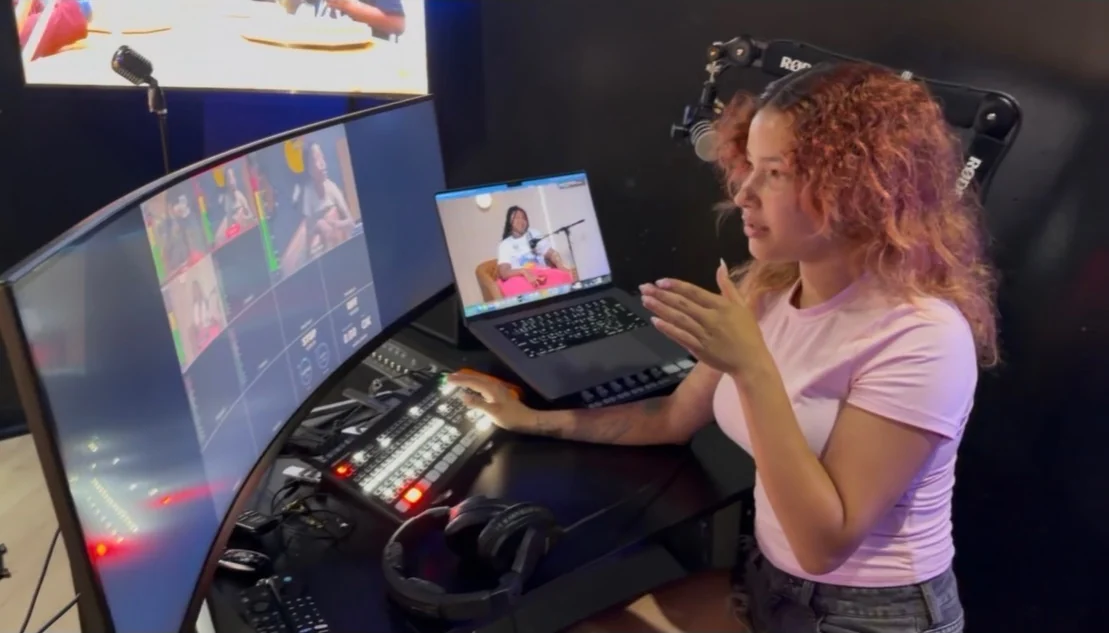 A young participant operating a video production switcher and multi-camera screens