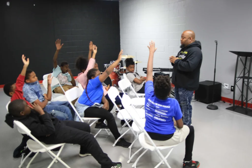 Young people raising their hands during a group discussion at Reed’s Refuge Center